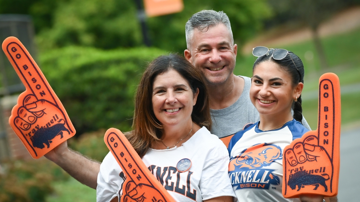 A Bucknell student and their parents wearing Bucknell #1 foam fingers