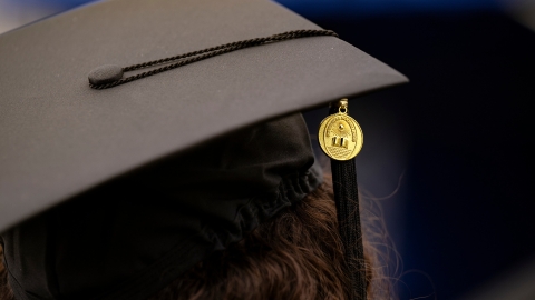 A close-up photo of a graduation cap with a Bucknell medallion and tassel