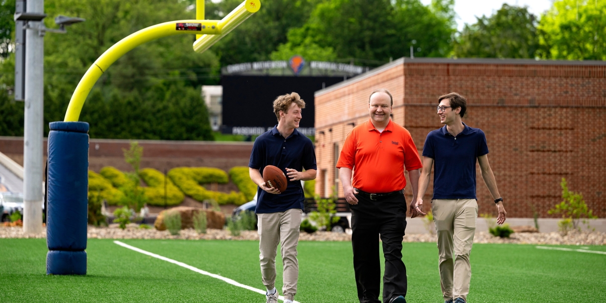 Professors Sam Gutekunst (right) and Joe Wilck (center) discuss an NFL-related research project with student Max Wilson '27 (left)